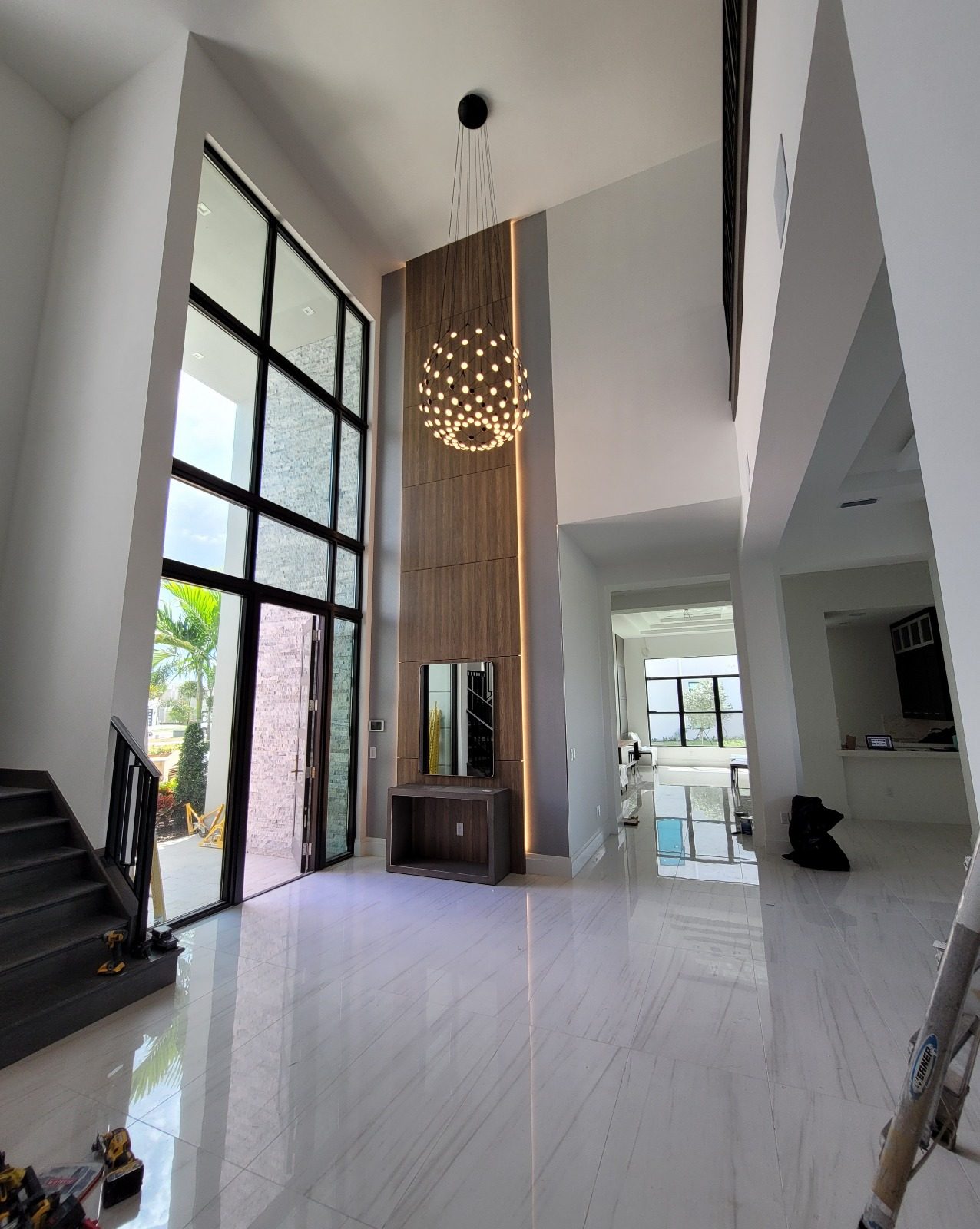 Completed two-story entrance with a tall wood feature wall and chandelier